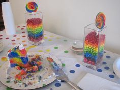 a table topped with lots of colorful candies next to two vases filled with lollipops