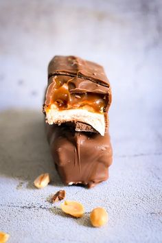 a chocolate bar with peanut butter and caramel on top, sitting on a blue surface