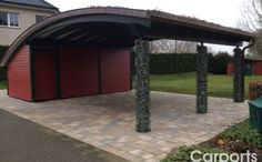 a red garage sitting next to a lush green yard