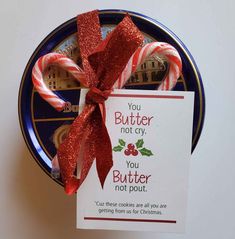 two candy canes wrapped in red ribbon with a card attached to the end that says, you butter not gay