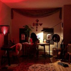 a woman sitting at a table in front of a red light on top of a rug