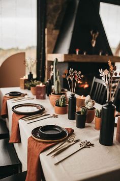 the table is set with black and white plates, utensils and succulents