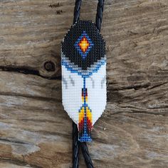 a beaded keychain with a cross on it sitting on a piece of wood