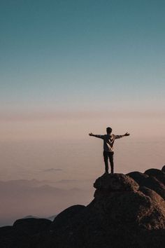 a man standing on top of a mountain with his arms outstretched