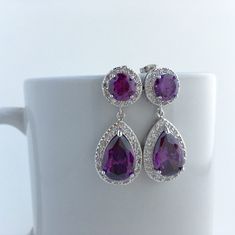 Large purple amethyst cubic zirconia bridal tear drop earrings in rhodium plated brass setting. Earrings feature a large teardrop with pear cut purple amethyst cubic zirconia center surrounded by tiny round zirconia crystals. Teardrop dangles from a earstud with brilliant cut purple amethyst cubic zirconia center and surrounded by tiny round zirconia crystals. This entire halo setting gives a brilliantly beautiful effect. Total length of the earring is 3.5 cms. For matching necklace click: https Purple Cubic Zirconia Earrings, Elegant Purple Cubic Zirconia Crystal Earrings, Purple Amethyst Teardrop Earrings For Pierced Ears, Purple Cubic Zirconia Earrings With Sparkling Stones, Purple Cubic Zirconia Earrings For Pierced Ears, Elegant Purple Crystal Earrings, Purple Sparkling Stone Drop Earrings, Elegant Purple Teardrop Crystal Earrings, Purple Drop Bridal Earrings As Gift