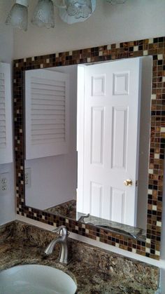 a bathroom sink sitting under a mirror next to a white door with shutters on it