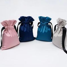 three satin drawsacks are lined up in different colors and sizes on a white background