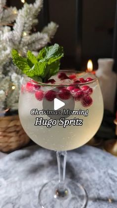 a glass filled with liquid sitting on top of a table next to a christmas tree