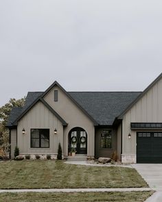 a house that is in the middle of some grass and has two garages on each side