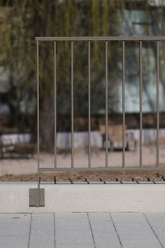 there are many birds sitting on the ground near a fence with bars and benches in the background