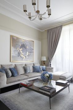 a living room filled with furniture and a chandelier above a glass coffee table