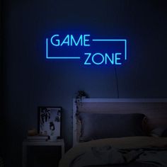 a neon sign that reads game zone on the wall above a bed in a dark room