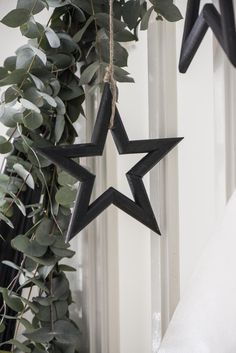 two black stars hanging from the side of a white wall next to a green plant