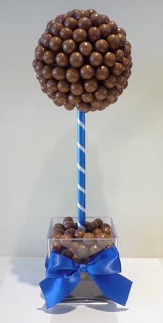 a blue candy cane with chocolate covered candies in it and a bow on the top