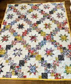 a quilt is laying on the floor with many different colored stars and flowers all over it