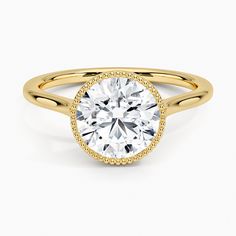 a yellow gold engagement ring with a round cut diamond in the center and pave set shoulders