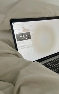 an open laptop computer sitting on top of a bed next to a pillow and blanket