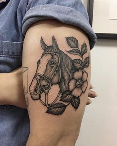 a woman's arm with a horse and flowers tattoo on the left side of her leg