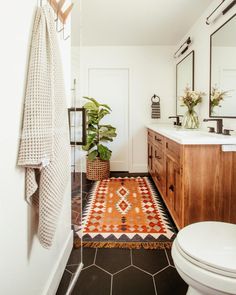 a white toilet sitting next to a wooden cabinet in a bathroom on top of a tiled floor