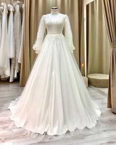 a white wedding dress on display in a bridal room with curtains and drapes