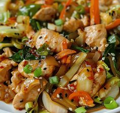 a white plate topped with chicken and veggies covered in sesame seed sauces