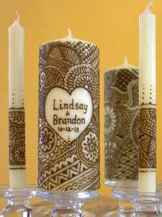 wedding candles are decorated with paisley designs and hearts for the couple's names on them