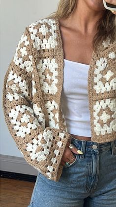 a woman is brushing her teeth with an electric toothbrush while wearing a crocheted jacket