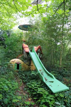 an abandoned playground in the woods with a slide