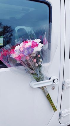 a bunch of flowers sitting on the side of a white car door with plastic wrap around it