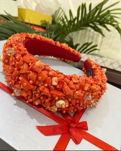 an orange headband with red ribbon and beads on the top, sitting on a table