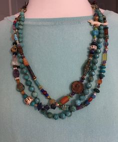 "Southwestern necklace that stars with jeans or silk. One strand is beautiful, hand-knotted faceted turquoise. The additional strands are filled with African trade beads, animals, flowers and a Willendorf female figure. Amethyst, carnelian, lapis and carved bone. Two moving manipulative features. Adjustable from 16\" to 39\"." Southwestern Multi-strand Adjustable Beaded Necklaces, Southwestern Multi-strand Necklace With Gemstone Beads, Bohemian Multi-strand Long Necklace With Faceted Beads, Bohemian Multi-strand Polished Beaded Necklace, Bohemian Multi-strand Polished Bead Necklace, Southwestern Necklace, African Trade Beads, Bone Carving, Trade Beads