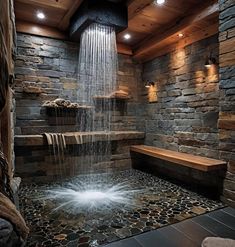 a large waterfall in the middle of a room with stone walls and wood flooring