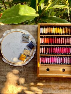 a wooden table topped with lots of different colored crayons and paintbrushes