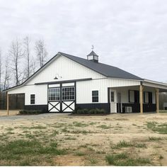 a large white barn with a black and white door on the side of it's building