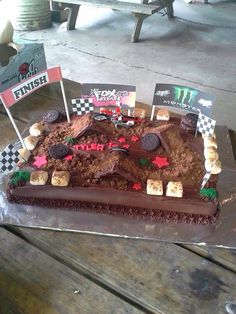 a cake that is sitting on top of a wooden table with flags in the shape of race cars