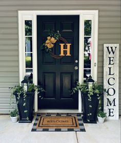 the front door is decorated with potted plants and a welcome sign that says h