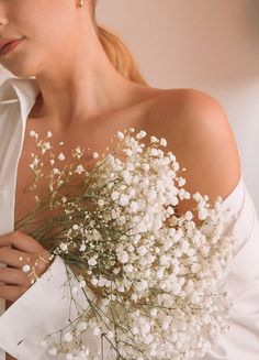 a woman wearing a white shirt and holding a bouquet of baby's breath flowers