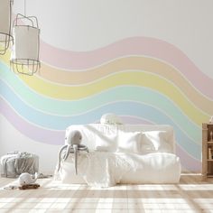 a white couch sitting on top of a wooden floor in front of a rainbow painted wall