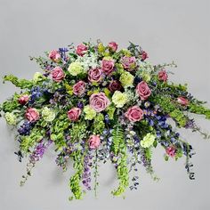 an arrangement of flowers on a white background with purple and green foliage in the center