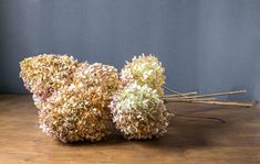 three dried flowers sitting on top of a wooden table