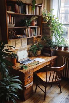 a laptop computer sitting on top of a wooden desk next to a plant filled window