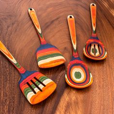 three wooden spoons with painted designs on them sitting next to each other and one has a fork in the middle