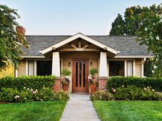 a house that is in the middle of some grass and flowers on the front lawn