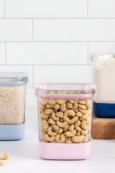 two containers filled with cashews on top of a counter next to other food items