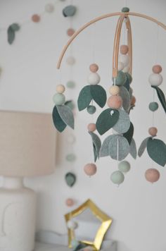 a baby mobile with leaves and balls hanging from it's side in a room