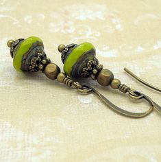 These not very large avocado green drop earrings are boho chic in style and dangle from brass earwires. The beads have a fantastic brownish patina and are faceted around their widest part to both give a clear view of their true color and add sparkle. The patina gives them an ancient,