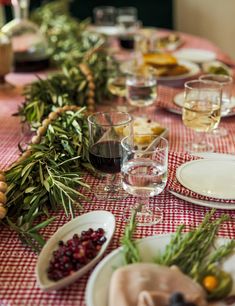 the table is set with plates, glasses and fruit on it for a festive dinner