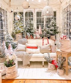 a living room filled with lots of furniture and christmas trees in front of the windows