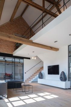 an empty living room with wooden floors and white walls is pictured in this image, there are two televisions on the wall