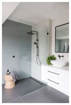 a modern bathroom with grey tile and white fixtures, including a walk - in shower